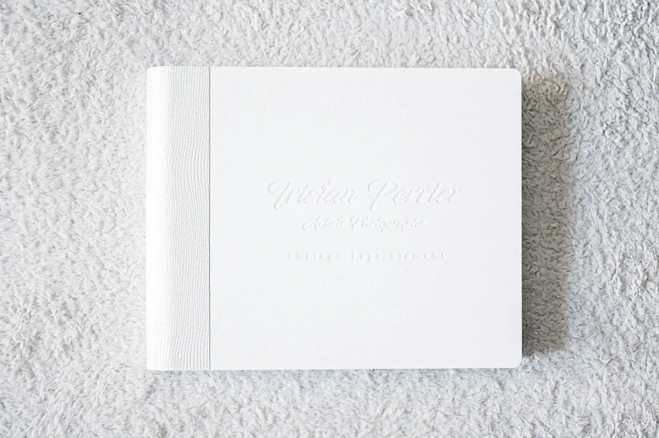 Luxury white leather wedding photo book resting on a soft rug