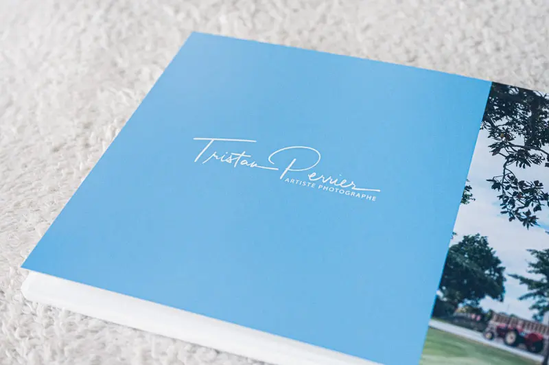 Pochette bleue au logo du photographe glissée sur un livre photo de mariage
