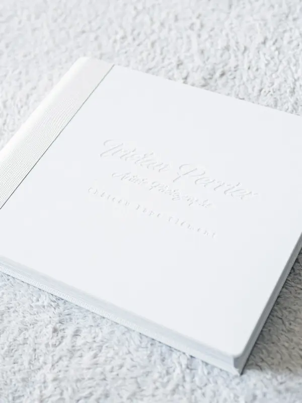 Album de mariage en cuir blanc à la couverture gravée, vu en biais