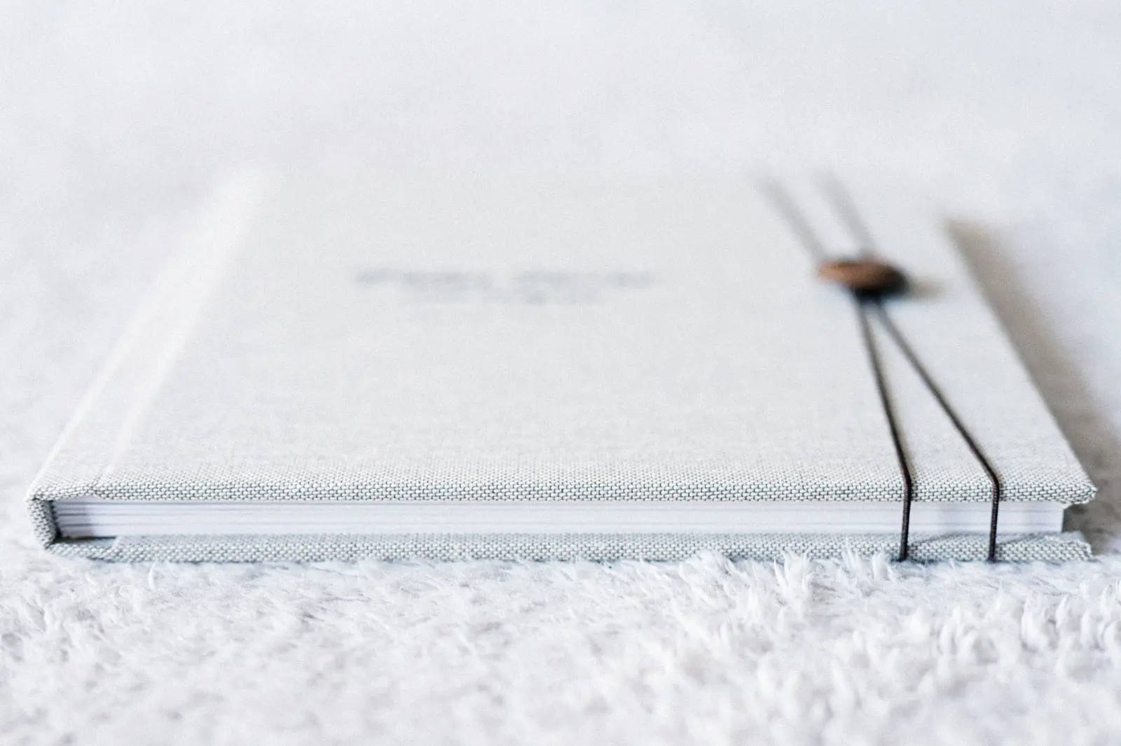 Pale linen family photo book closed with a cord and wooden button