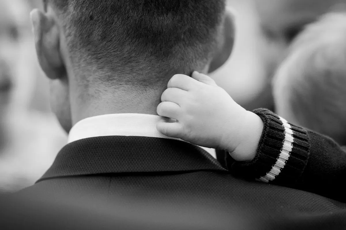 Child's small hand on the shoulder of a father in a suit, black and white