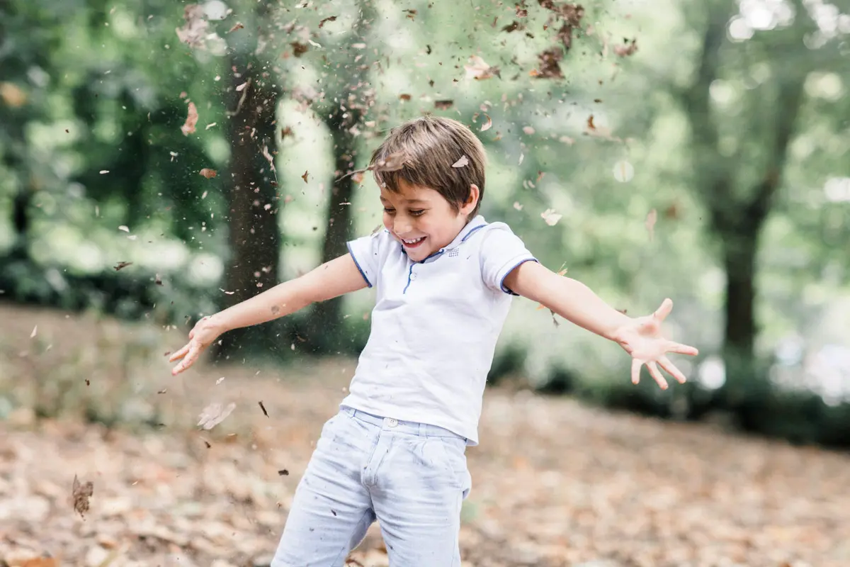 Little boy throwing autumn leaves in the air at the Parc Bordelais