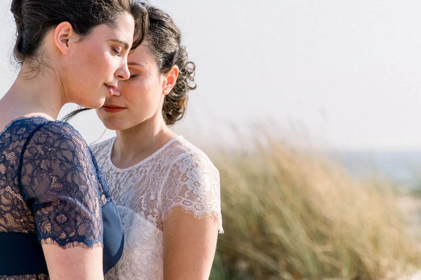 Two women embracing forehead to forehead by the Cap Ferret dunes