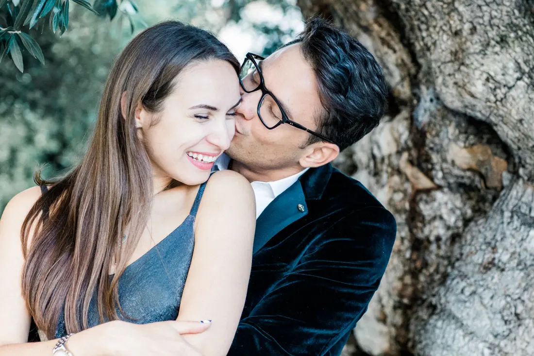 Smiling couple embracing against a rock during a photo session in Bordeaux