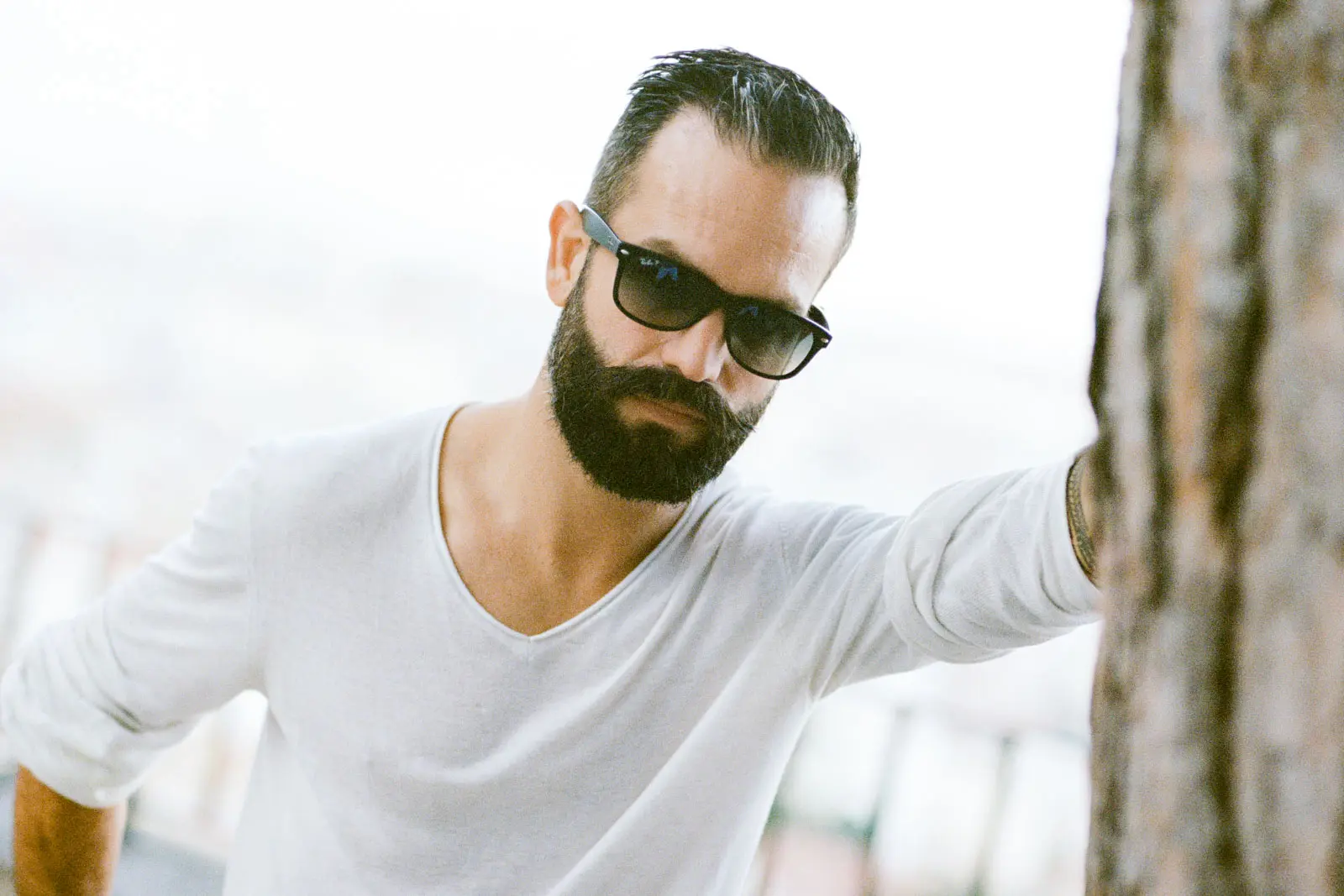 Bearded dad in sunglasses leaning on a tree, family session in Lisbon