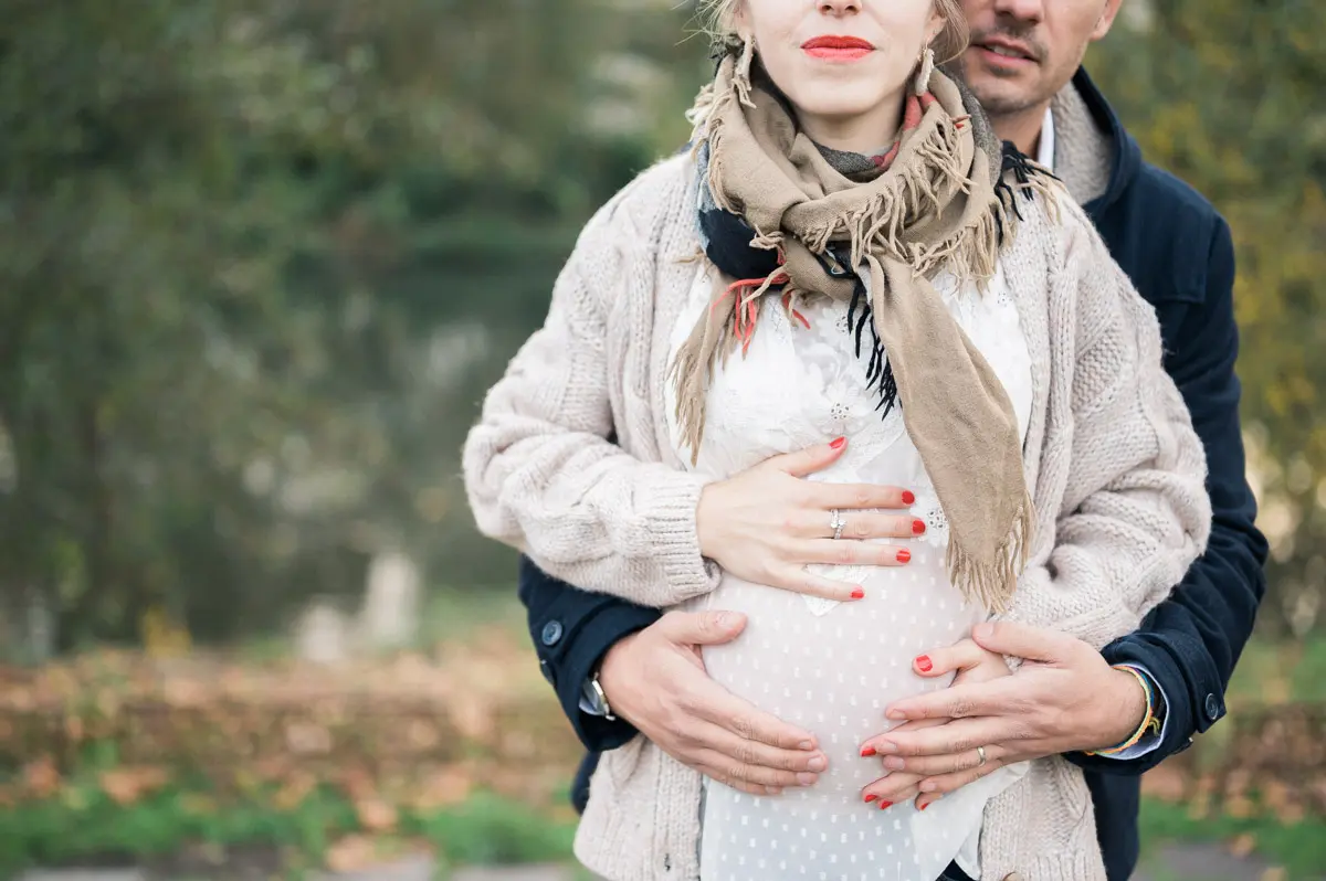 Future maman et son compagnon, mains sur le ventre, lors d'une séance grossesse à Mérignac