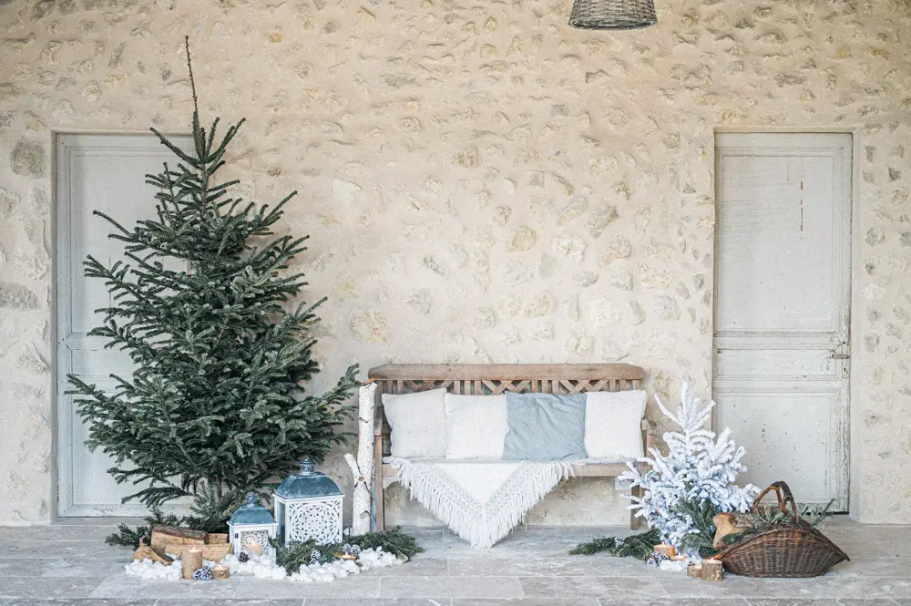 Winter decor at La Grange de Nicolas: fir tree, bench and lanterns against a stone wall