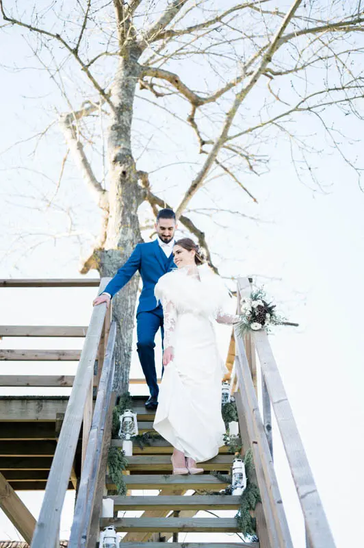 Bride and groom walking down the treehouse stairs under a winter sky