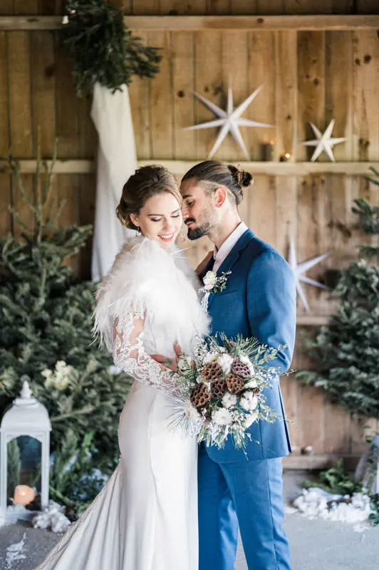 Bride in a fur stole nestled against the groom in a blue suit
