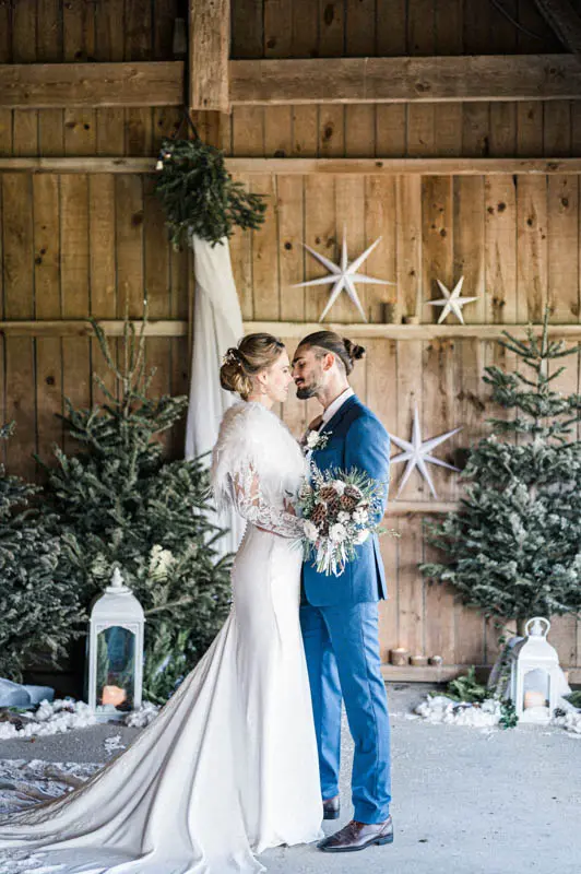 Bride and groom forehead to forehead before the barn's fir and star decor