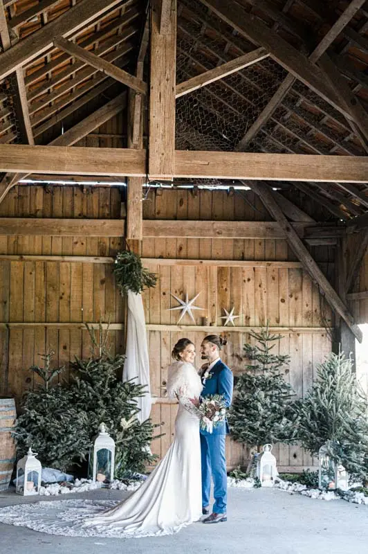 Wide view of the wooden barn and its winter decor around the couple