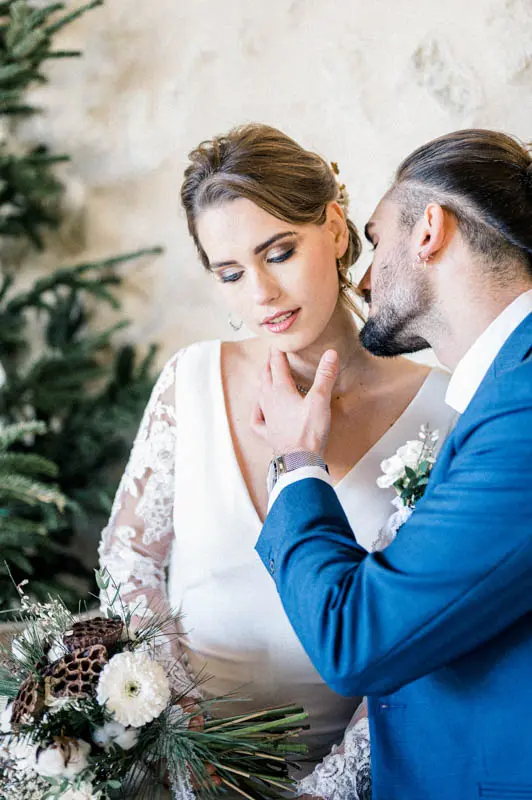 Groom kissing the bride's temple as she holds a winter bouquet