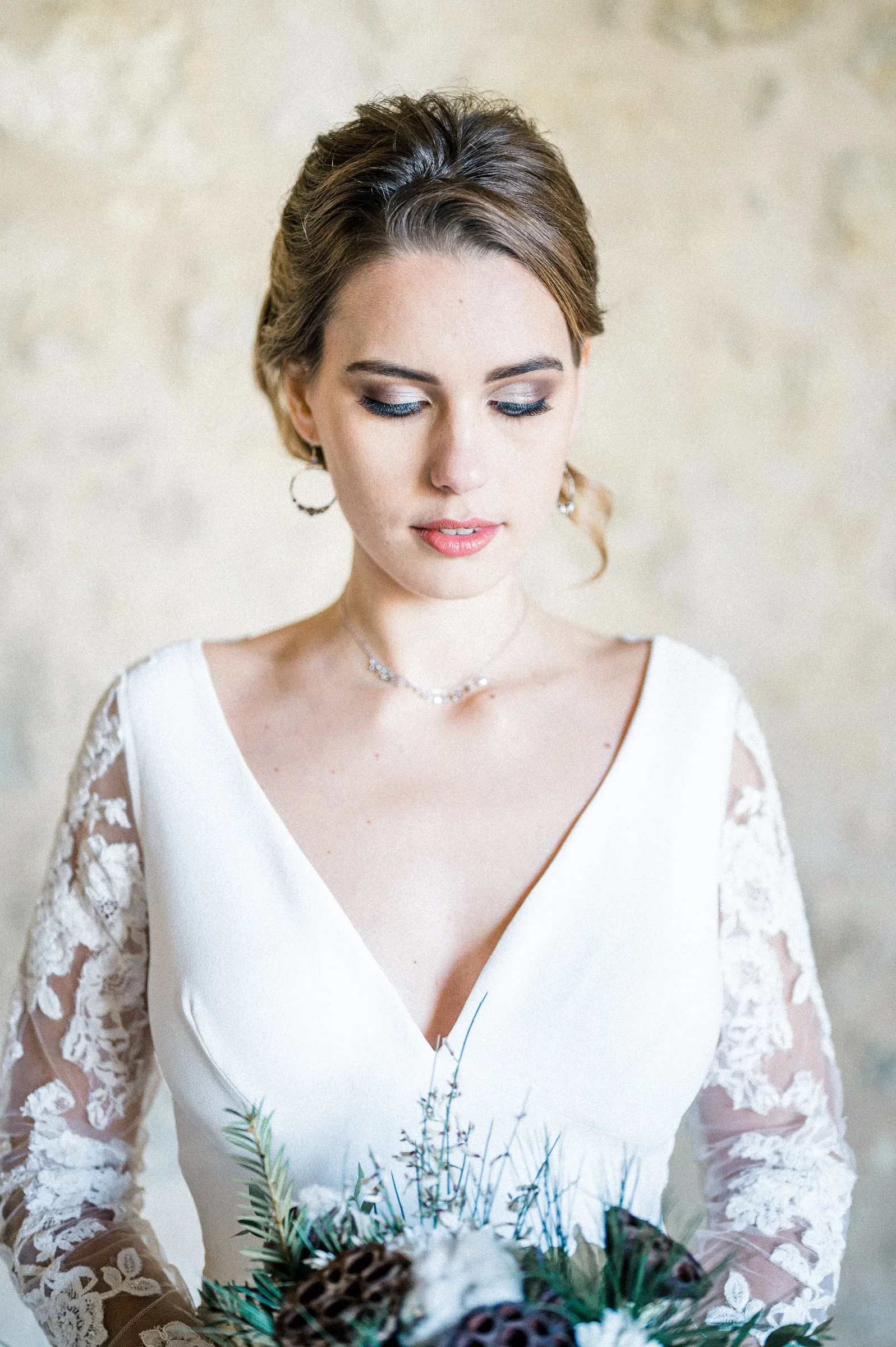 Portrait de la mariée au chignon, regard baissé, robe à décolleté en V