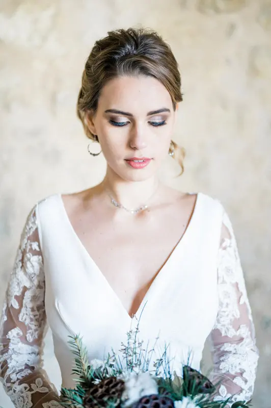 Portrait of the bride with an updo, eyes lowered, in a V-neck gown