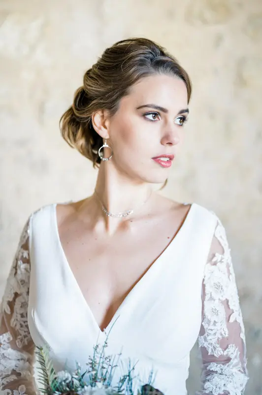 Bride with an updo turning her head, wearing hoop earrings