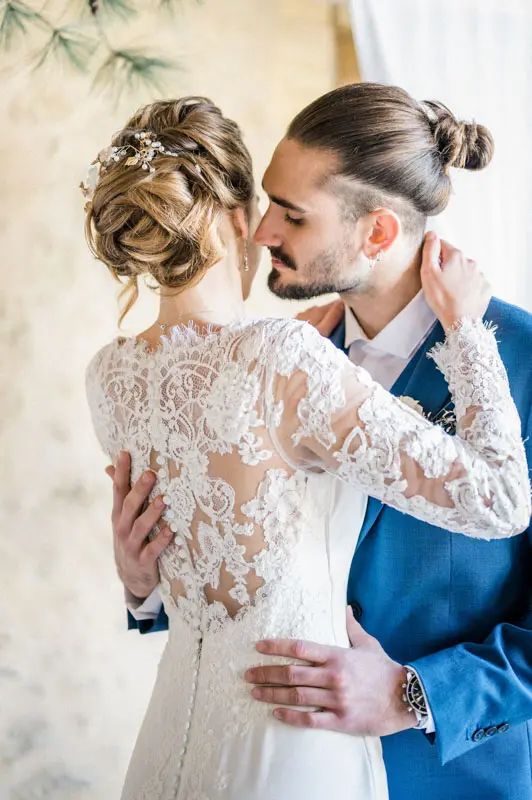 Groom kissing the bride's cheek, her lace back on display
