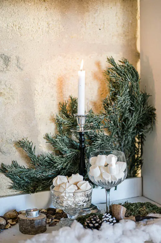 Marshmallow bar and candle surrounded by fir branches and pine cones