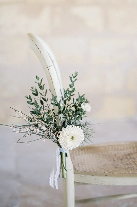 Bouquet of white flowers and greenery tied to the back of a chair