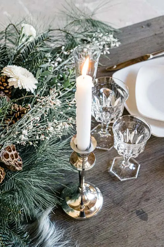 Winter centrepiece with a candle, crystal glasses and pine branches