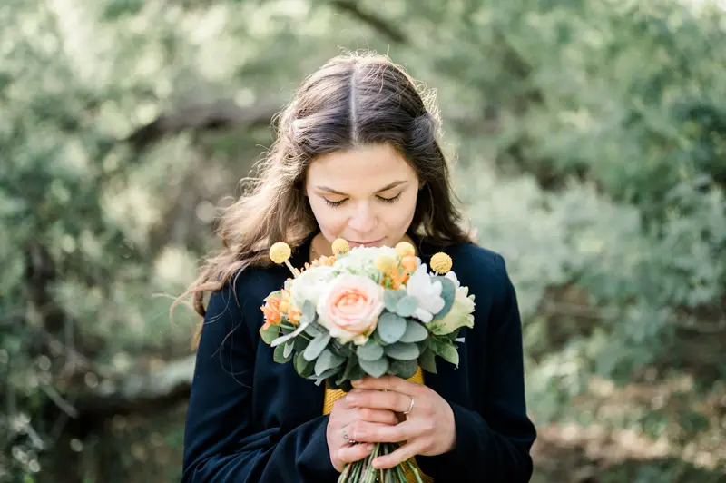 The bride-to-be smelling her bouquet of peach roses and white flowers