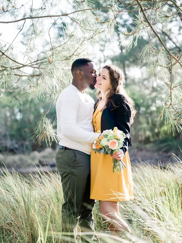 He kisses her temple as they stand among the wild grasses