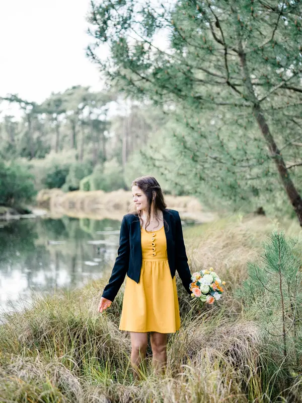 The bride-to-be alone by the pond, holding her bouquet