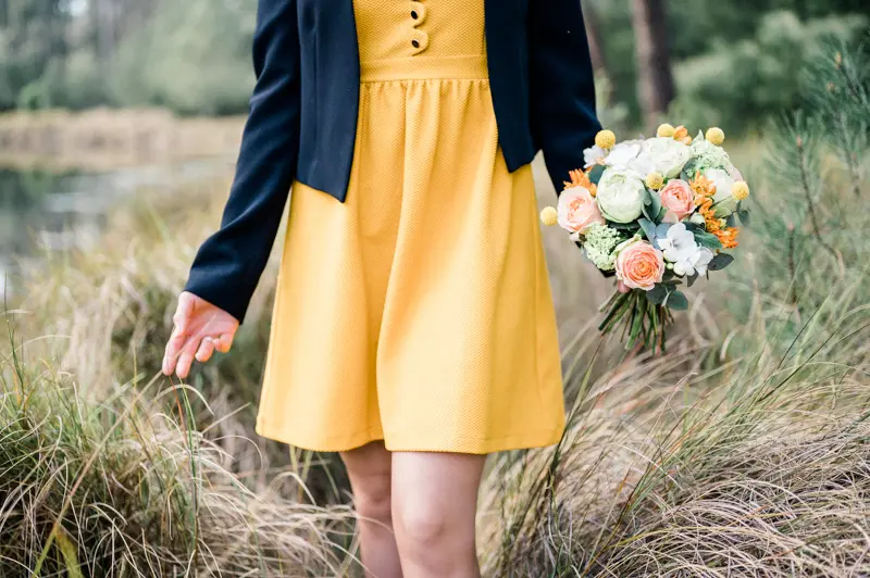 The yellow dress and bouquet brushing the tall grasses by the water