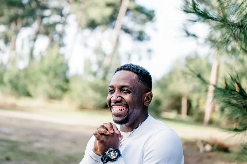 The groom-to-be bursting into laughter in the pine forest