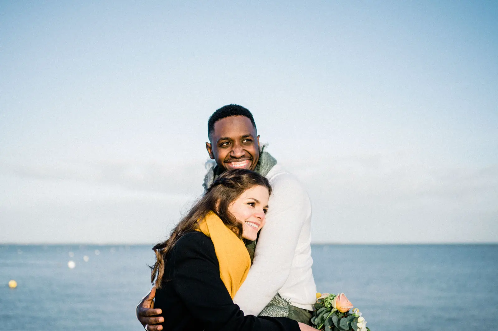 The couple embracing by the water during an engagement session on Arcachon Bay