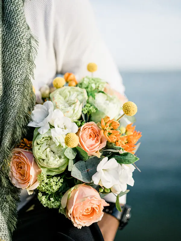 Close-up of the peach rose bouquet held against the water