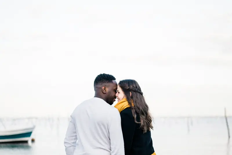 The couple forehead to forehead on the beach near a small boat