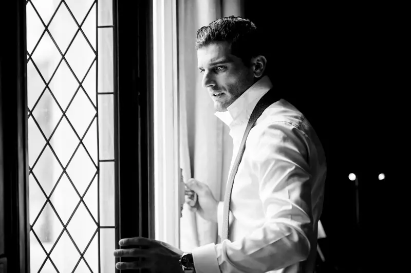 Giovanni getting ready by a lattice window, in black and white
