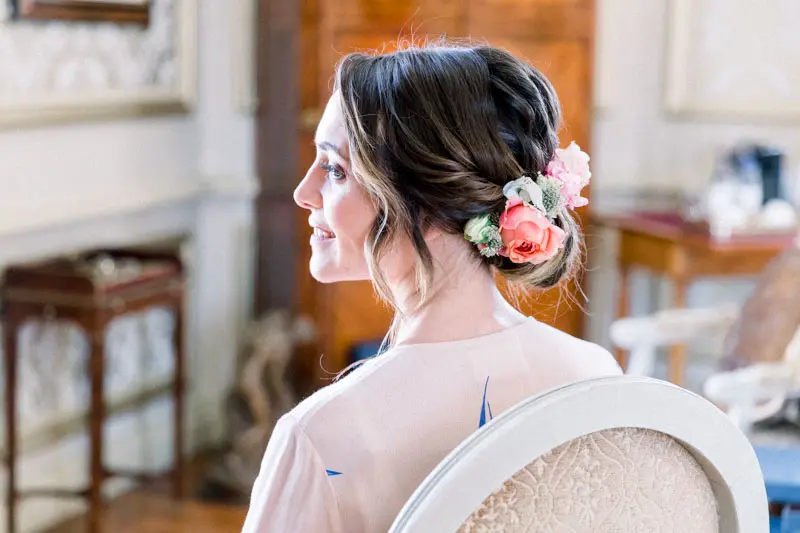 The bride seen from behind, her braided hair adorned with roses