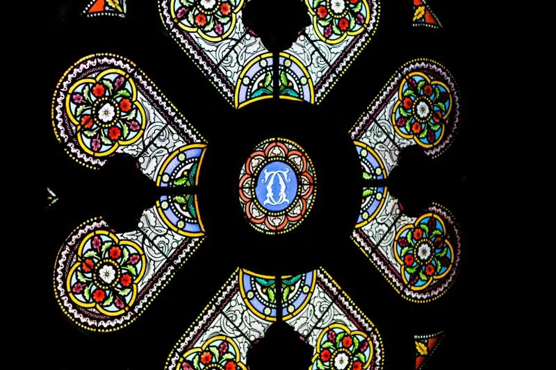 Colourful stained glass rose window against a dark background