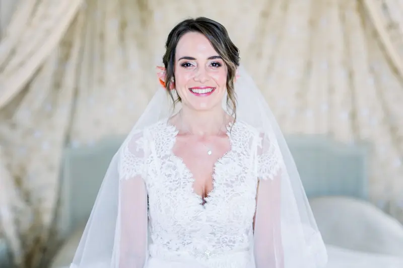 The smiling bride under her lace veil as she gets ready