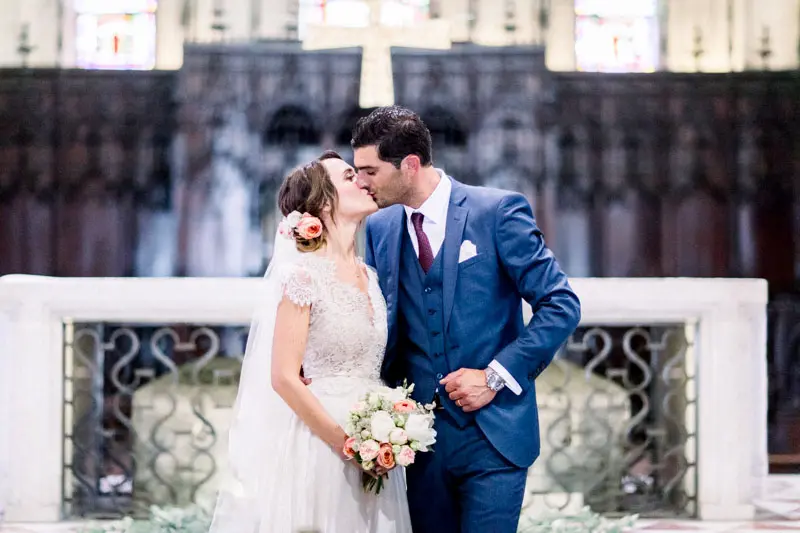 The bride and groom kissing in front of the Saint-Seurin altar
