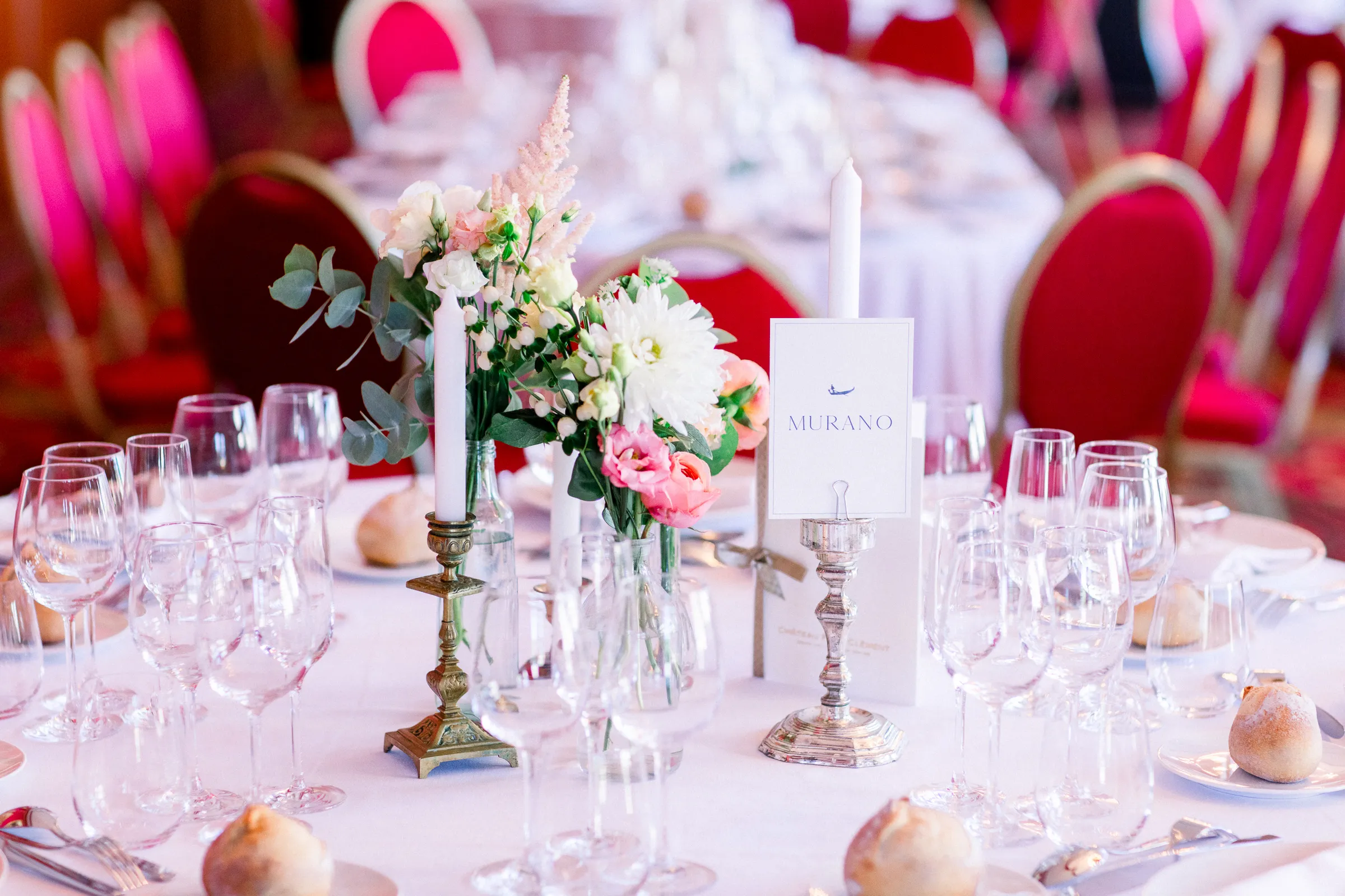 Table de réception avec chandeliers dorés, bouquet rose et chaises rouges