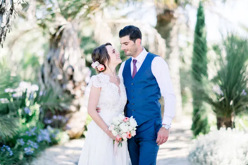 The bride and groom hand in hand in the château's exotic garden