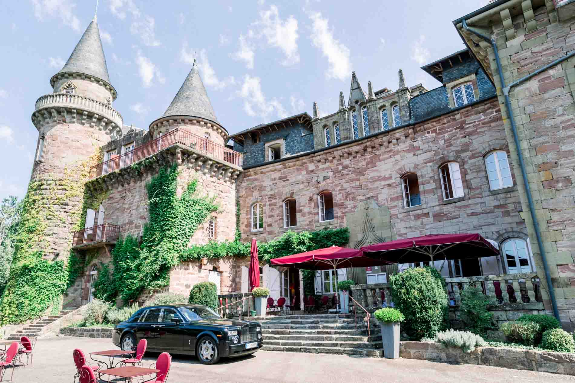 Brick facade of Château de Castel Novel with a classic car parked outside
