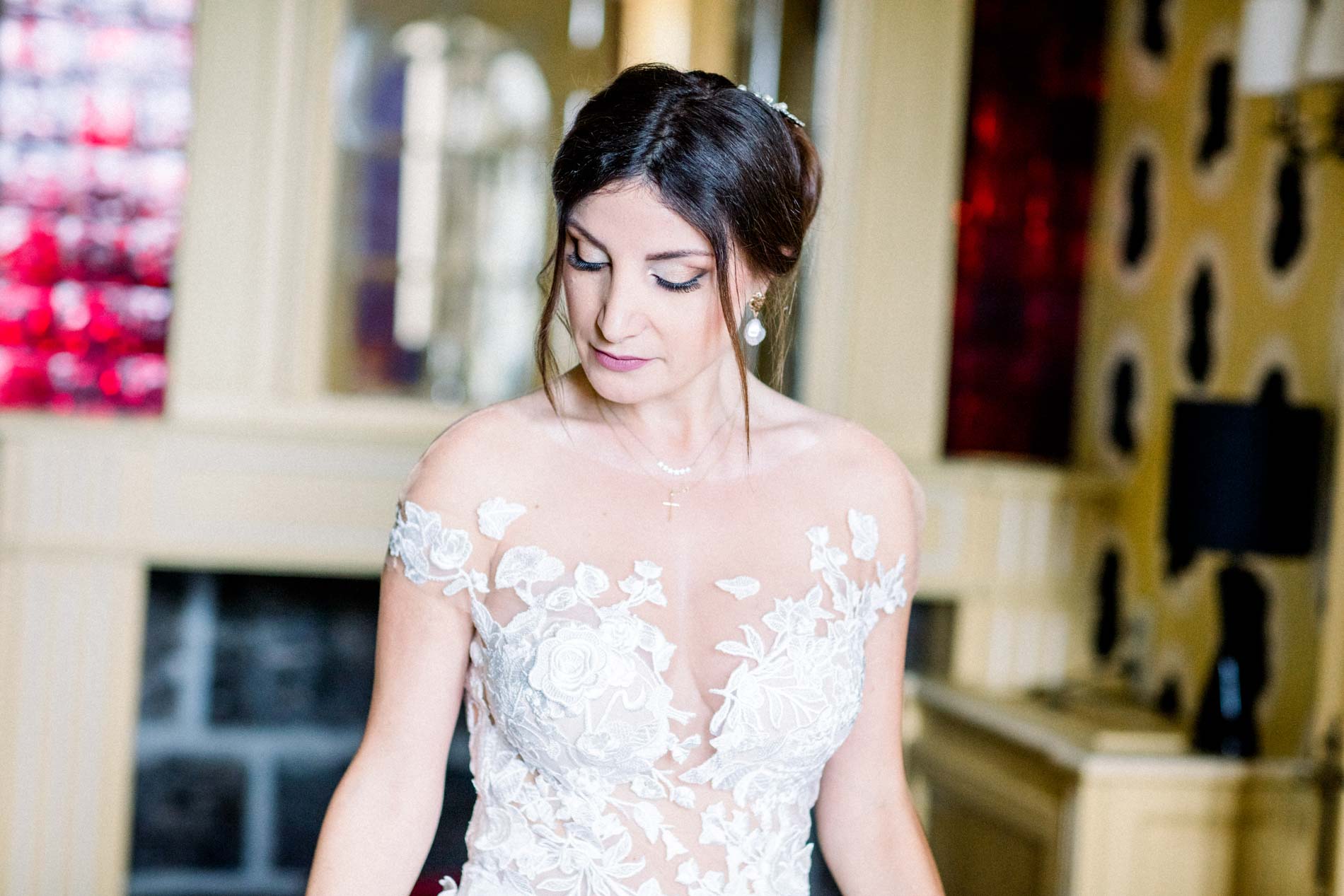 The bride in a floral embroidered gown adjusting her dress in her suite