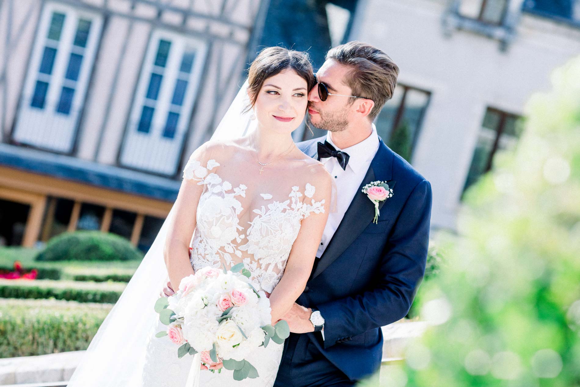 The bride and groom cheek to cheek in front of a half-timbered house