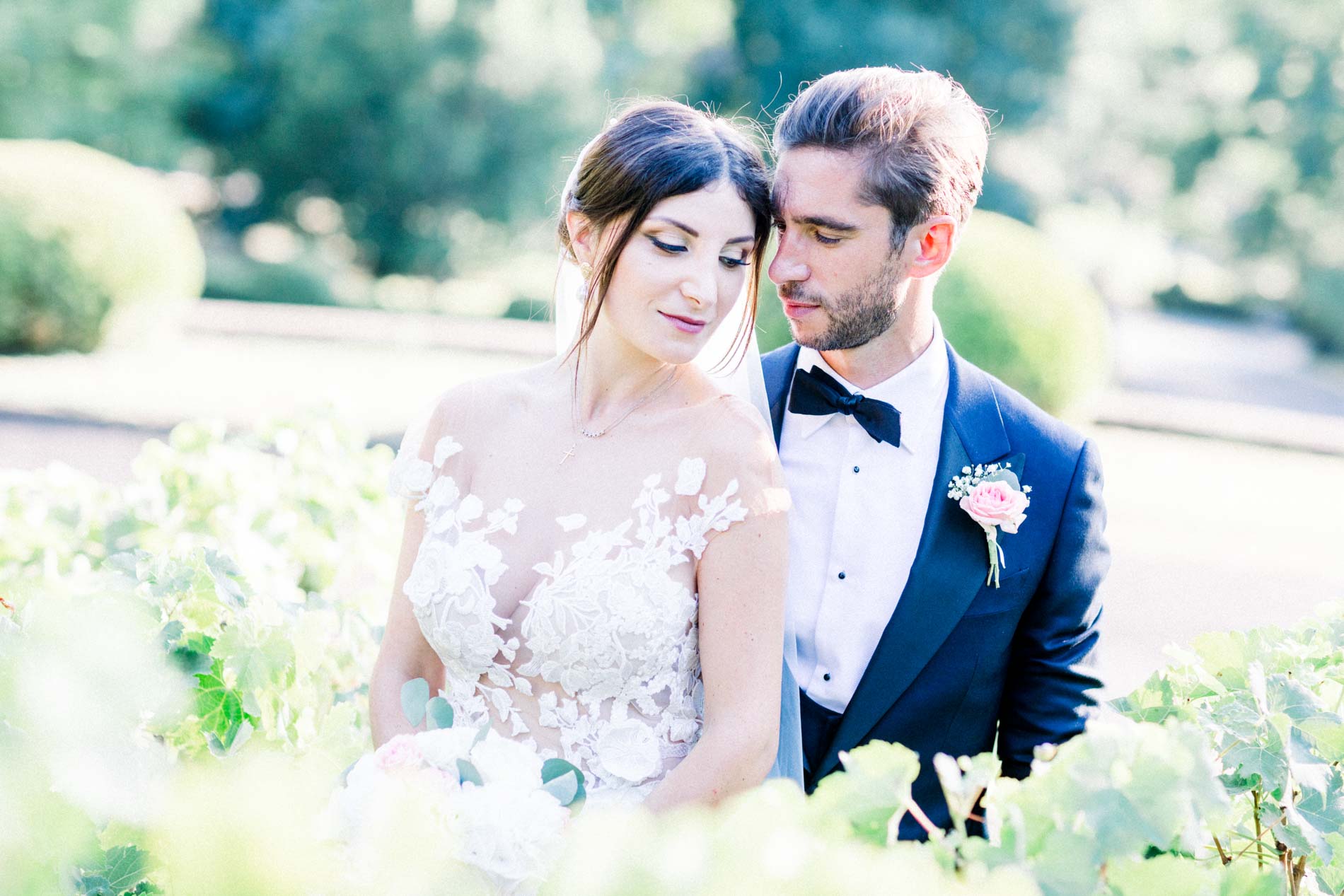 The bride with lowered eyes, the groom close beside her in the château gardens