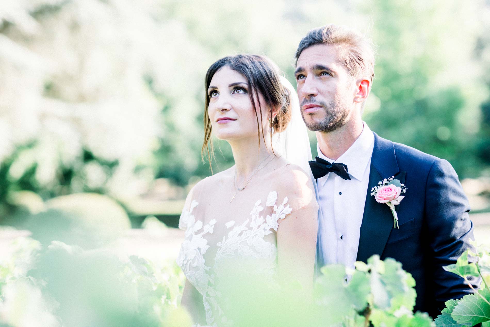 The bride and groom gazing into the distance side by side amid greenery