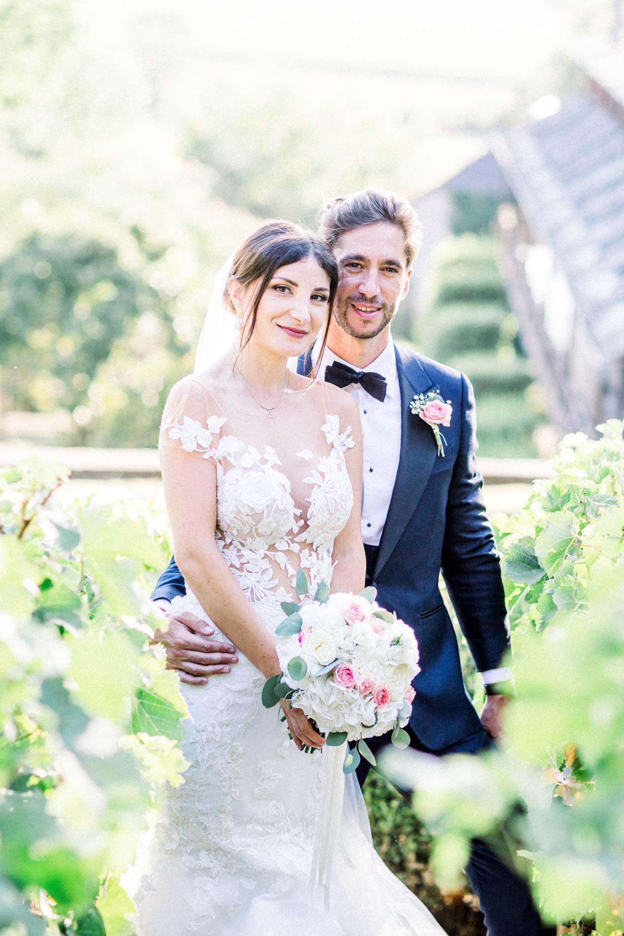 The groom holding the bride and her bouquet in the Castel Novel gardens