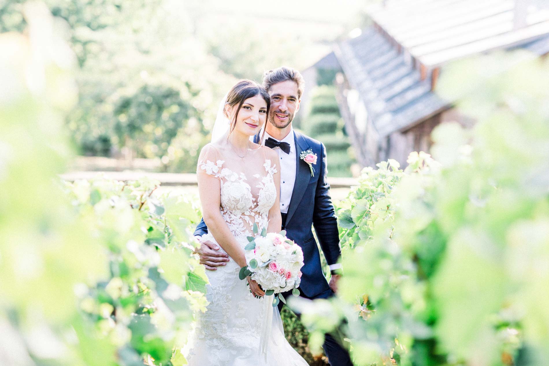 The couple embracing behind the foliage near a château staircase