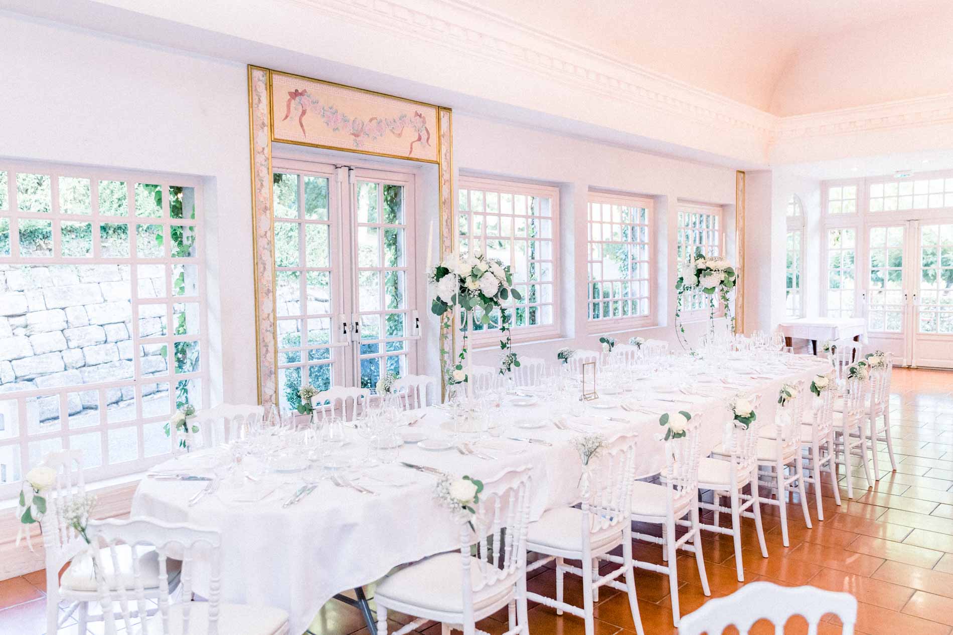 Bright reception room with long white tables at Château de Castel Novel
