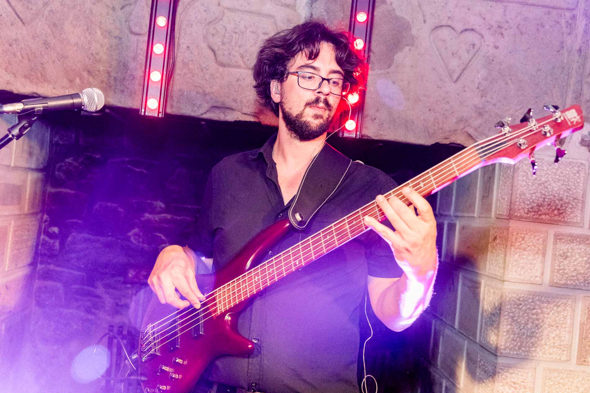 The bass player performing under purple lights at the party