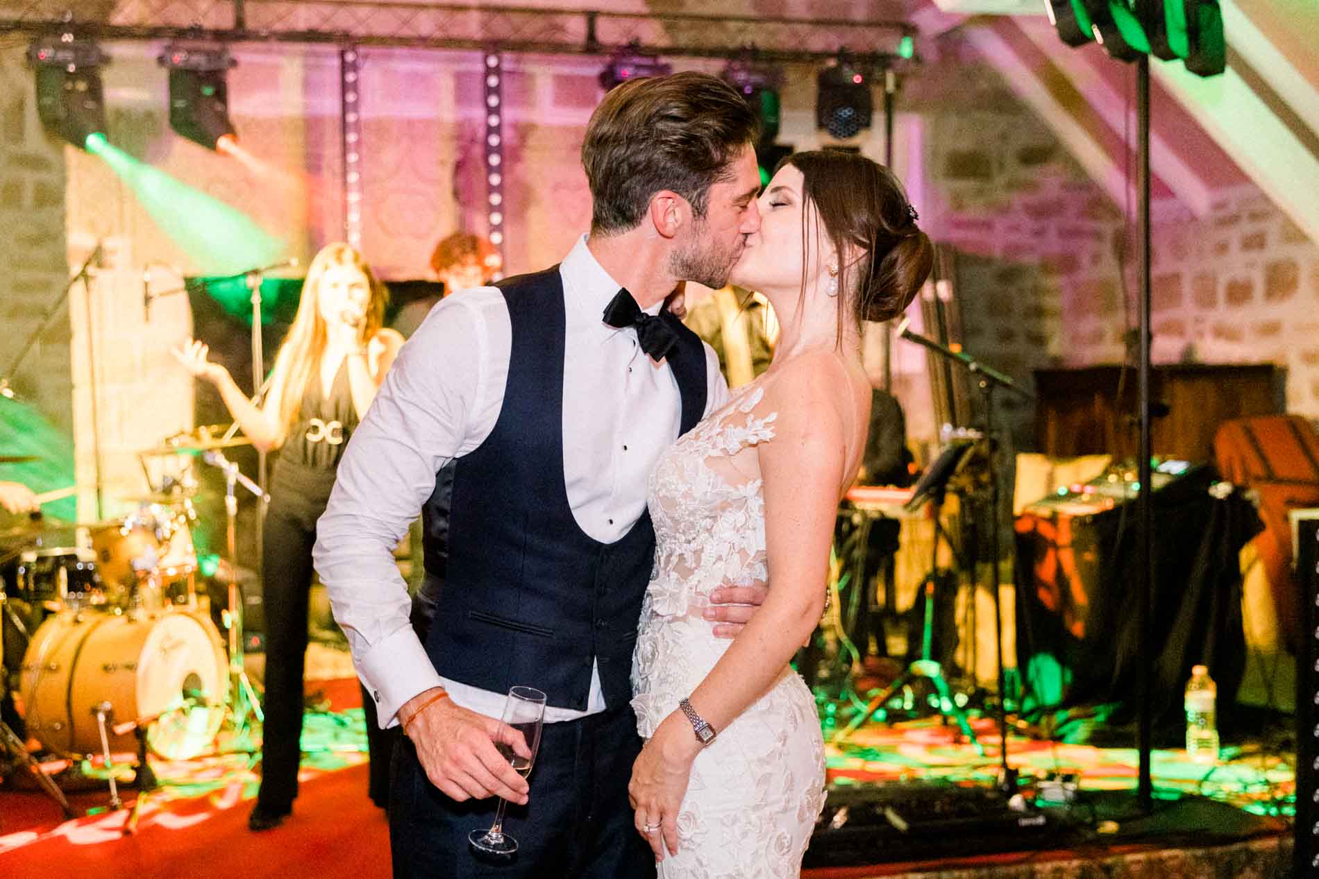 The bride and groom kissing on the dance floor in front of the band