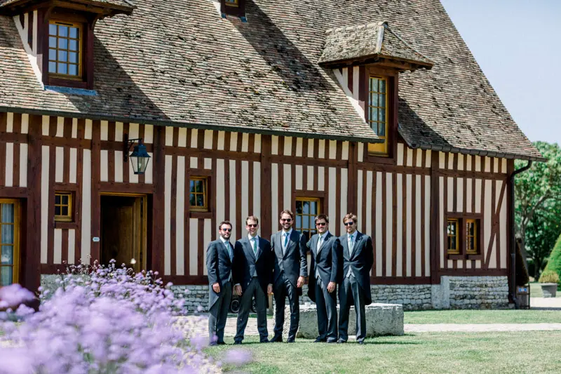 Le marié et ses amis devant une maison normande à colombages à Surville