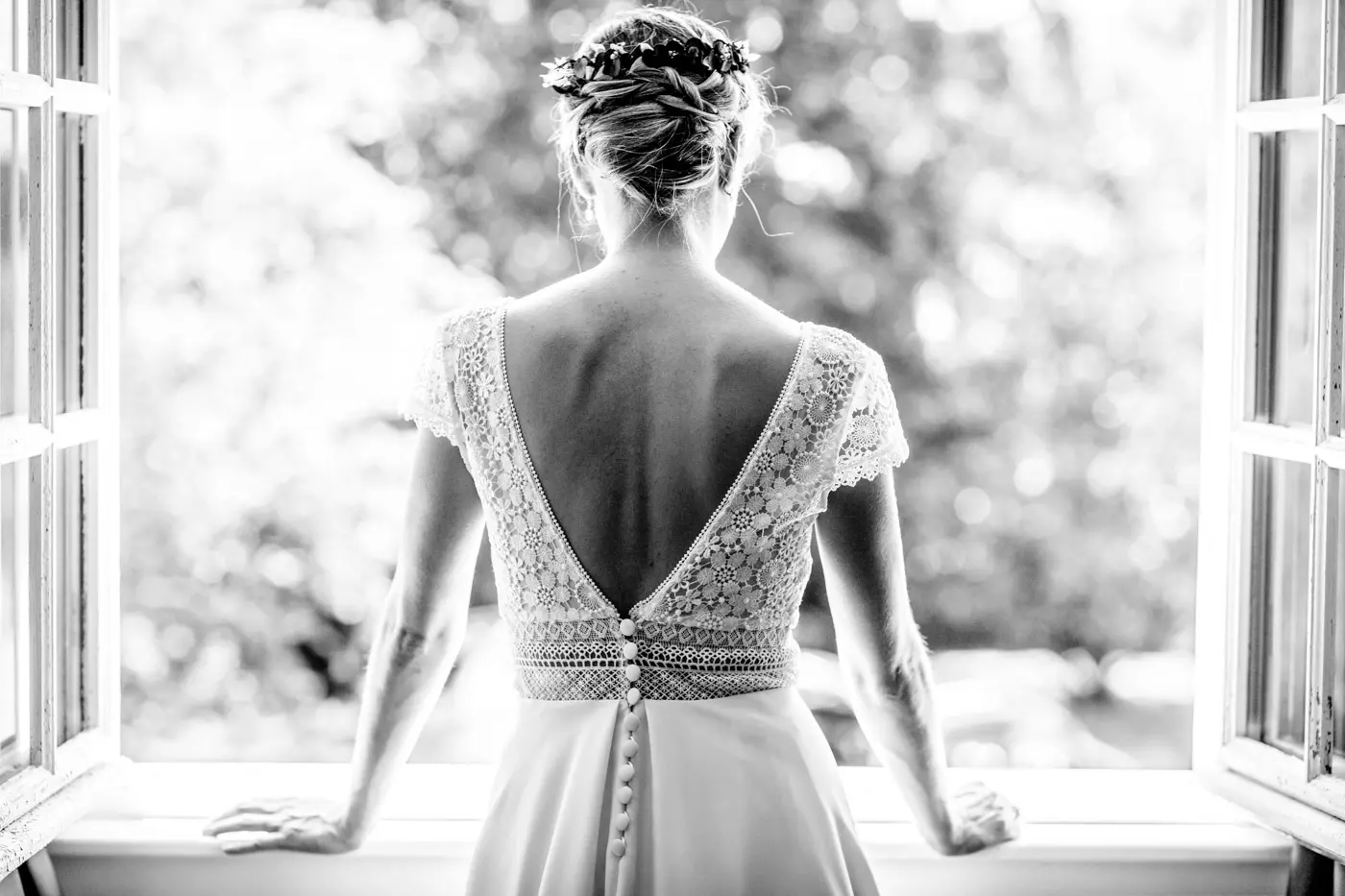 Mariée de dos devant une fenêtre ouverte, en noir et blanc